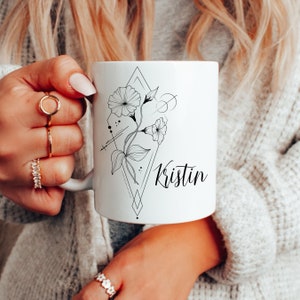 May include: White ceramic mug with a black and white floral design and the name "Kristin" printed on the front.