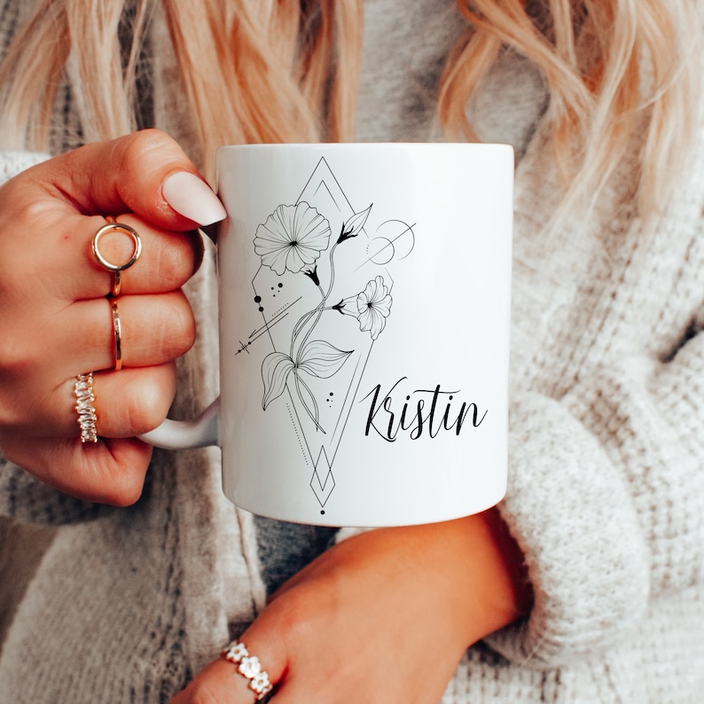 May include: White ceramic mug with a black and white floral design and the name "Kristin" printed on the front.