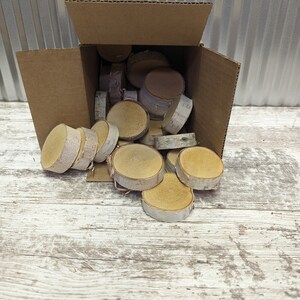 May include: A cardboard box overflowing with natural birch wood slices. The slices are various sizes and shapes, with a light brown colour and a natural white bark edge.