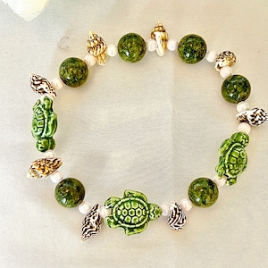 Beaded bracelet, jade beads, seashells, and sea turtles. White pearl bead accents. Comfortable stretch band. So pretty!