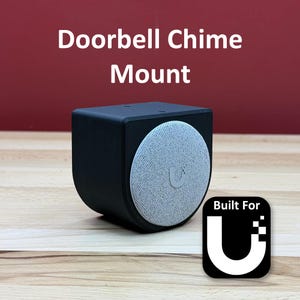 May include: A black doorbell chime mount with a circular speaker and the text "Doorbell Chime Mount." The speaker has a grey fabric cover with a "U" logo. The mount also features a "Built For U" logo.