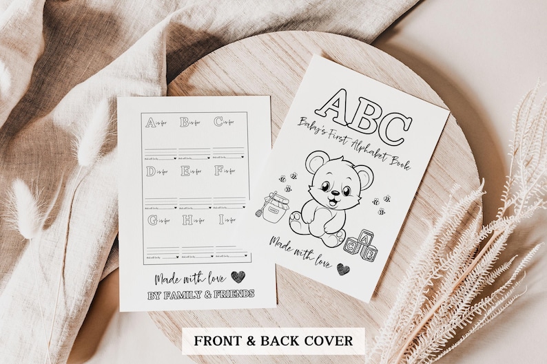 May include: Black and white printable front and back cover for a baby's first alphabet book. The front cover features a cartoon bear holding a jar of honey and the text "ABC Baby's First Alphabet Book". The back cover has a grid with the letters A through I and the text "Made with love by family and friends".
