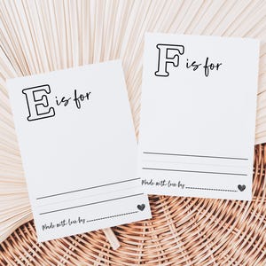 May include: Two white cards with black outlines of the letters E and F. The text "is for" is written next to each letter. The cards have a line for writing and the text "Made with love by..." at the bottom.