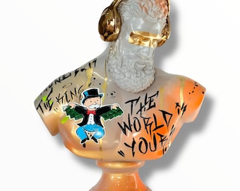 May include: A decorative bust with a white face, gold headphones, and gold sunglasses. The bust has a white beard and is painted with orange and gold accents. The words "THE KING" and "THE WORLD YOU" are written on the bust. A Monopoly character is also featured.