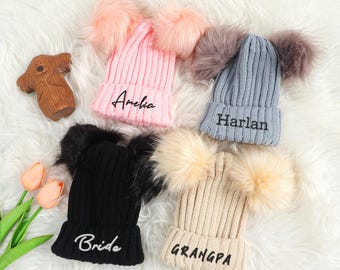Può includere: Quattro berretti di lana con pon pon rosa, nero, grigio e beige. Ogni berretto ha un nome diverso ricamato: Amelia, Bride, Harlan e Grandpa.