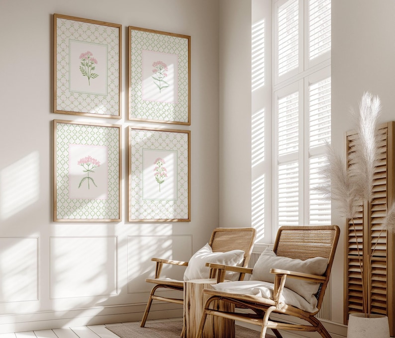 May include: Four framed botanical prints with pink flowers on a white background. The prints are arranged in a grid pattern on a white wall. Two wicker chairs with white cushions are in the foreground.