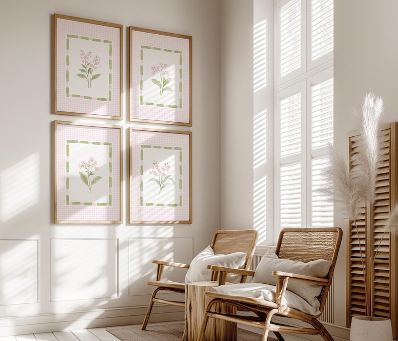 May include: Four framed floral art prints. Each print features a pink gingham background with a green border and a watercolor illustration of pink flowers. The frames are a light wood color. The prints are displayed above two wooden chairs.