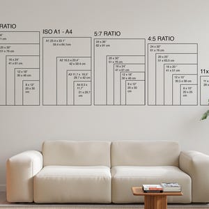 Puede incluir: Un sal&oacute;n moderno con un sof&aacute; blanco, una peque&ntilde;a mesa de madera y una planta en maceta. En la pared, gu&iacute;as de tama&ntilde;os enmarcadas en negro para varios formatos de impresi&oacute;n, incluyendo 2:3, ISO A1-A4, 5:7, 4:5 y 11x14, con medidas en cm.