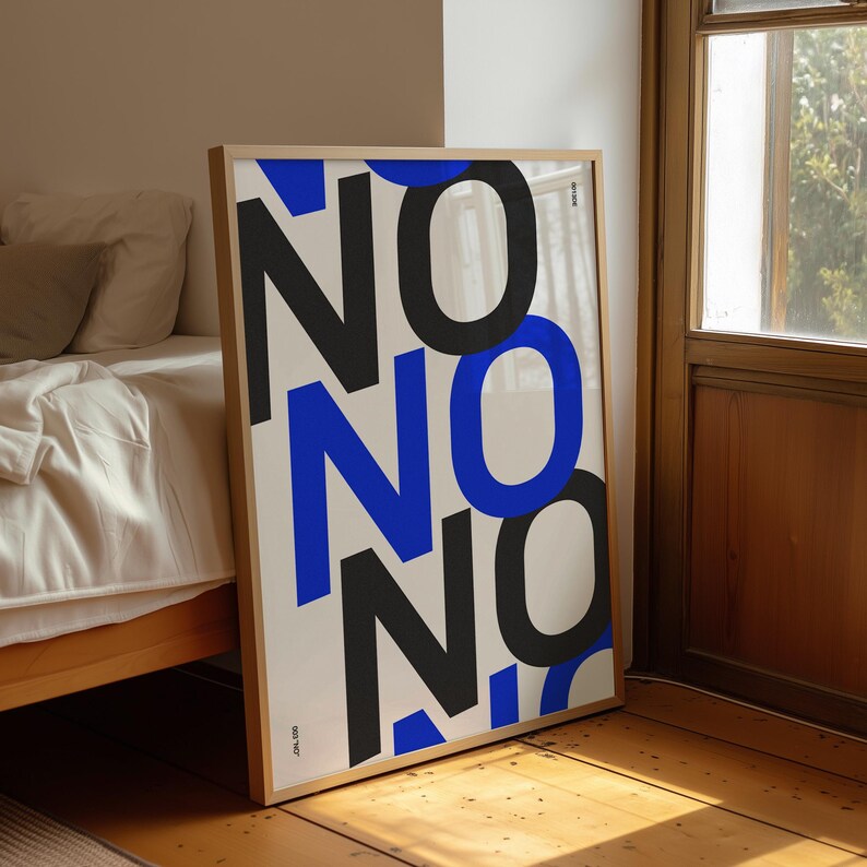 Puede incluir: Un cuadro enmarcado con la palabra "NO" repetida en letras grandes y audaces, negras y azules. La obra de arte se muestra sobre un fondo blanco y se apoya en una pared. El marco es de color madera clara.
