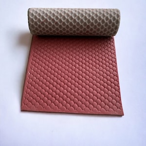 May include: A red rubber mat with a textured diamond pattern. The mat is rolled up and the underside is a light gray color.
