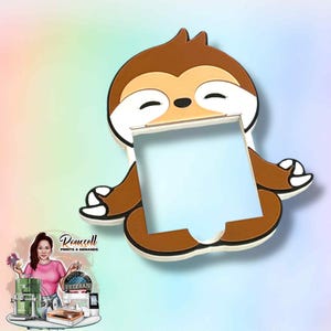 May include: A brown and white sloth-shaped picture frame. The sloth is in a seated yoga pose with its eyes closed. The frame has a light blue center. The image has a colorful background.