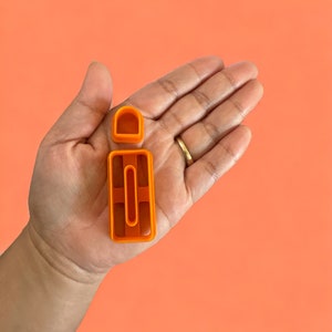 May include: Orange plastic letter I cookie cutter. The cookie cutter is in the shape of the letter I and has a small hole in the center.
