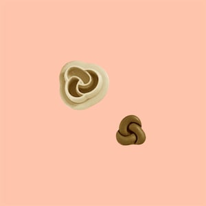 May include: Two plastic cookie cutters, one white and one brown, shaped like a three-leaf clover.