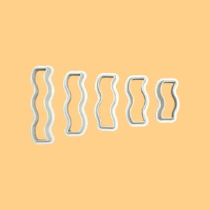May include: Set of five white plastic cookie cutters in different sizes, each with a wavy rectangular shape.