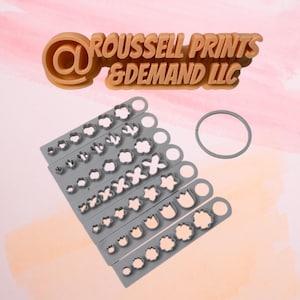 May include: A set of seven gray plastic cookie cutters with various flower and leaf shapes. The cutters are arranged in a row, with the largest cutter at the top and the smallest cutter at the bottom. The cutters are all made of a durable plastic and are perfect for making cookies, fondant, or other pastries.