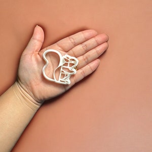 May include: White plastic cookie cutter shaped like a squirrel sitting on a branch.