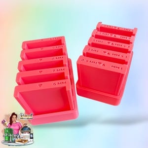 May include: Two sets of bright pink rectangular tools with measurements in millimeters. One set is labeled with measurements from 6 MM to 9 MM. The other set is labeled from 0.5 MM to 5 MM. The tools are in a tray.