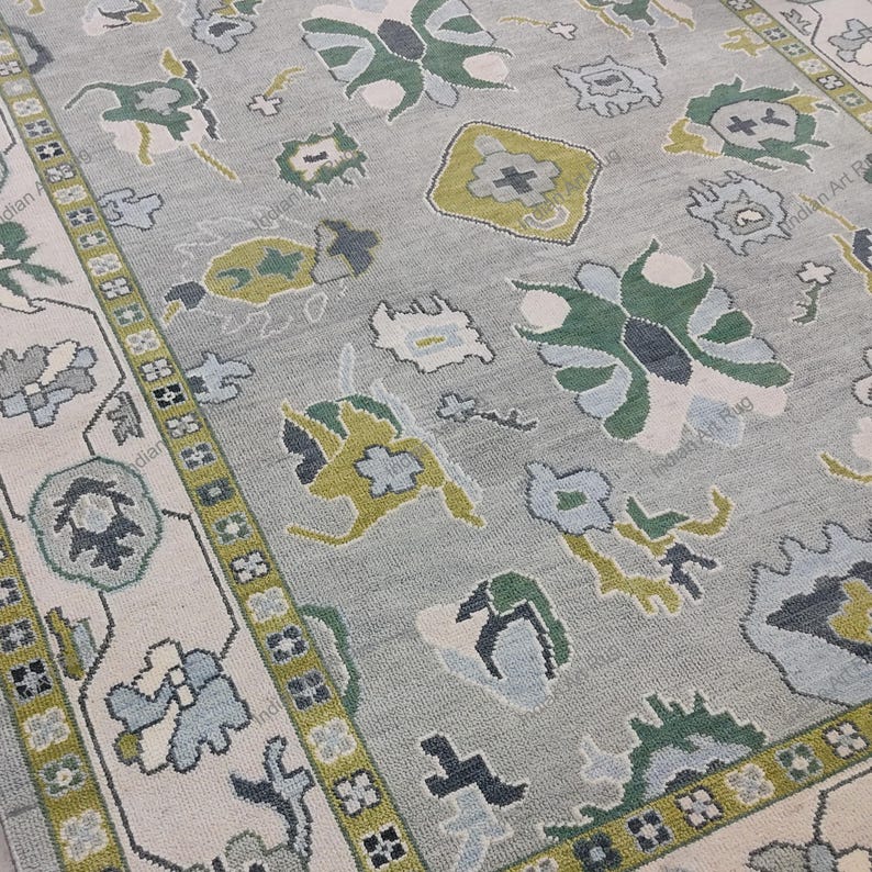 May include: A light gray rug with a floral pattern in shades of green, blue, and cream. The rug has a border with a repeating geometric design. The overall design is a traditional style.