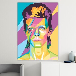 Könnte beinhalten: Ein Pop-Art-Porträt auf Leinwand. Das Kunstwerk zeigt eine farbenfrohe geometrische Darstellung eines Gesichts mit leuchtenden Farbtönen von Blau, Lila, Gelb und Grün. Das Porträt ist an einer weißen Wand angebracht.