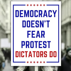 May include: A white sign with a blue border and text that reads "DEMOCRACY DOESN'T FEAR PROTEST DICTATORS DO" in blue and red. The sign has red stars at the top and bottom.