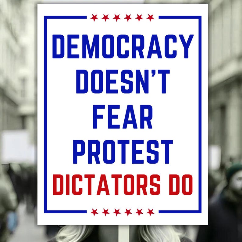 May include: A white sign with a blue border and text that reads "DEMOCRACY DOESN'T FEAR PROTEST DICTATORS DO" in blue and red. The sign has red stars at the top and bottom.