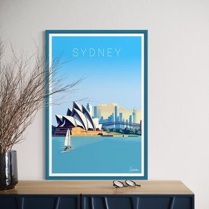 Peut inclure: Une affiche encadrée représentant une illustration stylisée de Sydney, en Australie. L'œuvre d'art représente l'Opéra de Sydney, un voilier, le pont du port de Sydney et la ligne d'horizon de la ville sous un ciel bleu. Le mot "SYDNEY" est imprimé en haut.