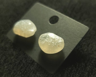 A pair of oval-shaped agate earrings, they are translucent with a yellowish hue and white speckles all over