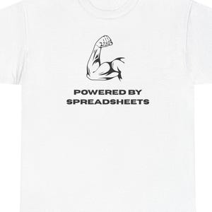 May include: A white short-sleeved t-shirt featuring a black graphic of a flexed bicep muscle centered on the chest. Below the graphic, the text reads POWERED BY SPREADSHEETS in a bold, black, sans-serif font. The shirt has a crew neckline.
