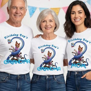May include: Three white t-shirts featuring a graphic of a blue snake wrapped around a fox and a rabbit. The text reads Birthday Boy's with the words GRANDPA, GRANDMA, or MOM below. The shirts are paired with blue denim jeans.