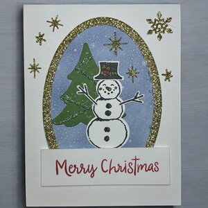 Carte de Noël bonhomme de neige avec flocons de neige dorés scintillants et motif festif