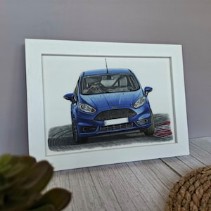 May include: A framed drawing of a blue hatchback car shown from a front-facing perspective. The vehicle features a black honeycomb grille, clear headlights, and a white license plate area, depicted as if driving on a curved track surface.