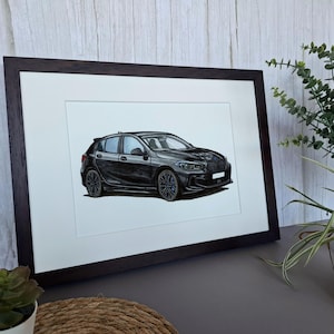 May include: A framed illustration of a black hatchback car shown from a side angle. The car features dark multi-spoke wheels, a sleek aerodynamic body, and a white license plate area. The artwork is presented in a dark brown wooden frame.