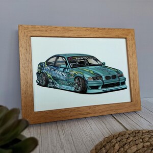 May include: A light blue drift car illustration in a wooden frame. The car features the text SPLIT MAGE and MATSURI on the windshield and body, with green flame-like graphics, low-profile tires, and a lowered suspension in a detailed drawing.