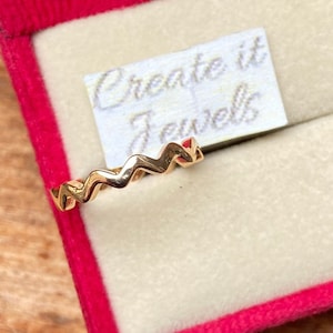 May include: A gold zig-zag patterned ring in a red velvet ring box with a white label that says "Create it Jewels".