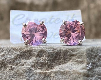 May include: A pair of silver stud earrings with pink round gemstones.