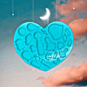May include: A blue silicone mold shaped like a heart with various designs, including a skull, lightning bolt, and a smiley face.