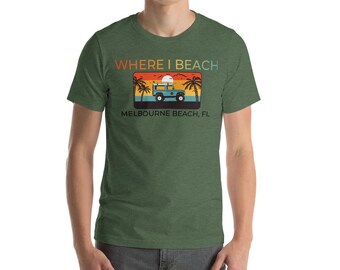May include: A green t-shirt with a retro-style graphic that says "Where I Beach" and "Melbourne Beach, FL". The graphic features a blue jeep with a surfboard on top, driving on a beach with palm trees and a sunset.