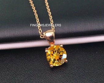 Puede incluir: Un collar de cadena de oro con un colgante con una piedra preciosa de citrino amarillo redonda.