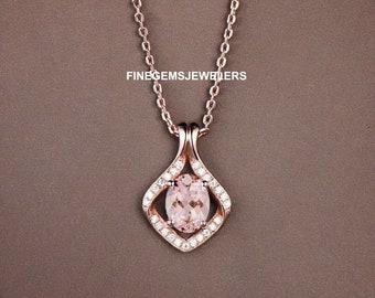May include: A rose gold necklace with a pendant featuring a large oval-shaped morganite gemstone surrounded by smaller diamonds. The pendant is set in a delicate, diamond-shaped frame.