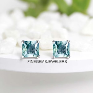 May include: A pair of silver stud earrings with square-shaped green and blue agate gemstones. The earrings are set against a white background.