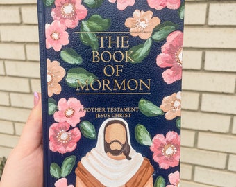 May include: A navy blue book with a floral design and the title "The Book of Mormon: Another Testament of Jesus Christ".