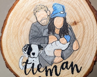 May include: A wooden round ornament with a painted image of a family with a dog. The family is a couple with a baby. The couple is wearing winter clothes. The dog is black and white. The ornament is decorated with the text "Tieman 2023".