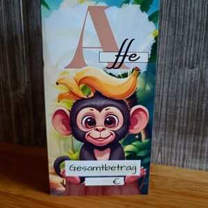 Könnte beinhalten: Eine farbenfrohe Karte mit einem Cartoon-Affen mit einer Banane auf dem Kopf. Der Affe hat große Augen und ist vor einem tropischen Hintergrund platziert. Die Karte enthält die Buchstaben "A" und "ffe", die Worte "Gesamtbetrag" und ein Euro-Symbol.