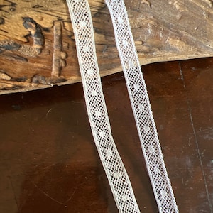 May include: Two white lace trims with a dotted pattern. The lace is delicate and has a soft, feminine feel.