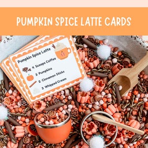 May include: A set of Pumpkin Spice Latte cards with a recipe for 4 scoops coffee, 3 pumpkins, 2 cinnamon sticks, and 3 whipped cream. The cards are displayed over a bowl filled with orange, brown, and pink pasta shapes, white pom-poms, and wooden scoops.