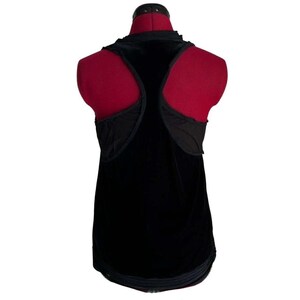 Puede incluir: Camiseta sin mangas de terciopelo negro con dise&ntilde;o de espalda nadadora. La parte superior presenta un cuello redondo y un ribete decorativo a lo largo del dobladillo inferior. La espalda tiene paneles de malla negra.