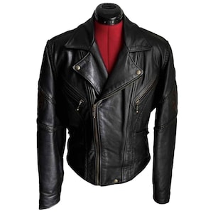 May include: Black leather jacket with a classic biker style. Features a notched collar, asymmetrical zipper closure, multiple zippered pockets, and decorative stitching. The jacket is displayed on a mannequin with a red torso.