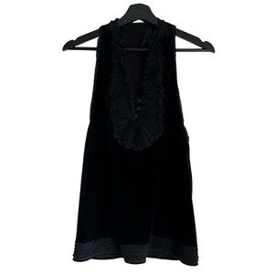 Puede incluir: Top negro sin mangas con cuello en V y ribete decorativo de volantes. La parte superior tiene tres botones peque&ntilde;os y un dobladillo gris en contraste. La prenda est&aacute; colgada de una percha negra.