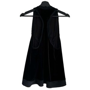 Puede incluir: Un chaleco de terciopelo negro cuelga de una percha negra. El chaleco tiene un cuello alto y un dise&ntilde;o frontal abierto. La tela parece suave y cae con elegancia. El dobladillo inferior est&aacute; adornado con un material m&aacute;s oscuro, similar al sat&eacute;n.