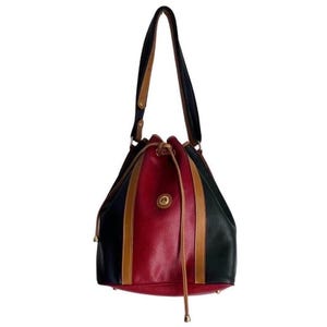 May include: A vintage bucket bag with a drawstring closure. The bag features a color-block design with black, red, and green panels, accented by tan stripes. The shoulder straps are black with tan trim, and the bag has a gold-tone emblem.